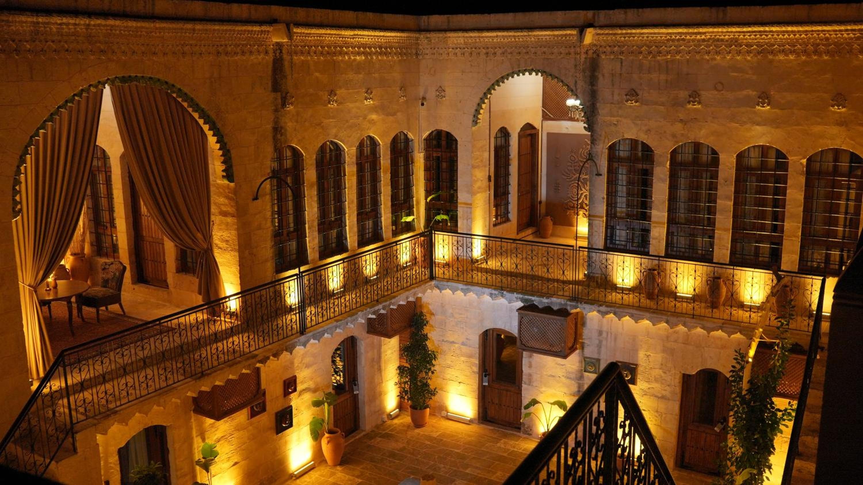 The illuminated stone courtyard of Stone House by Cevahir at night, with arched galleries on two floors