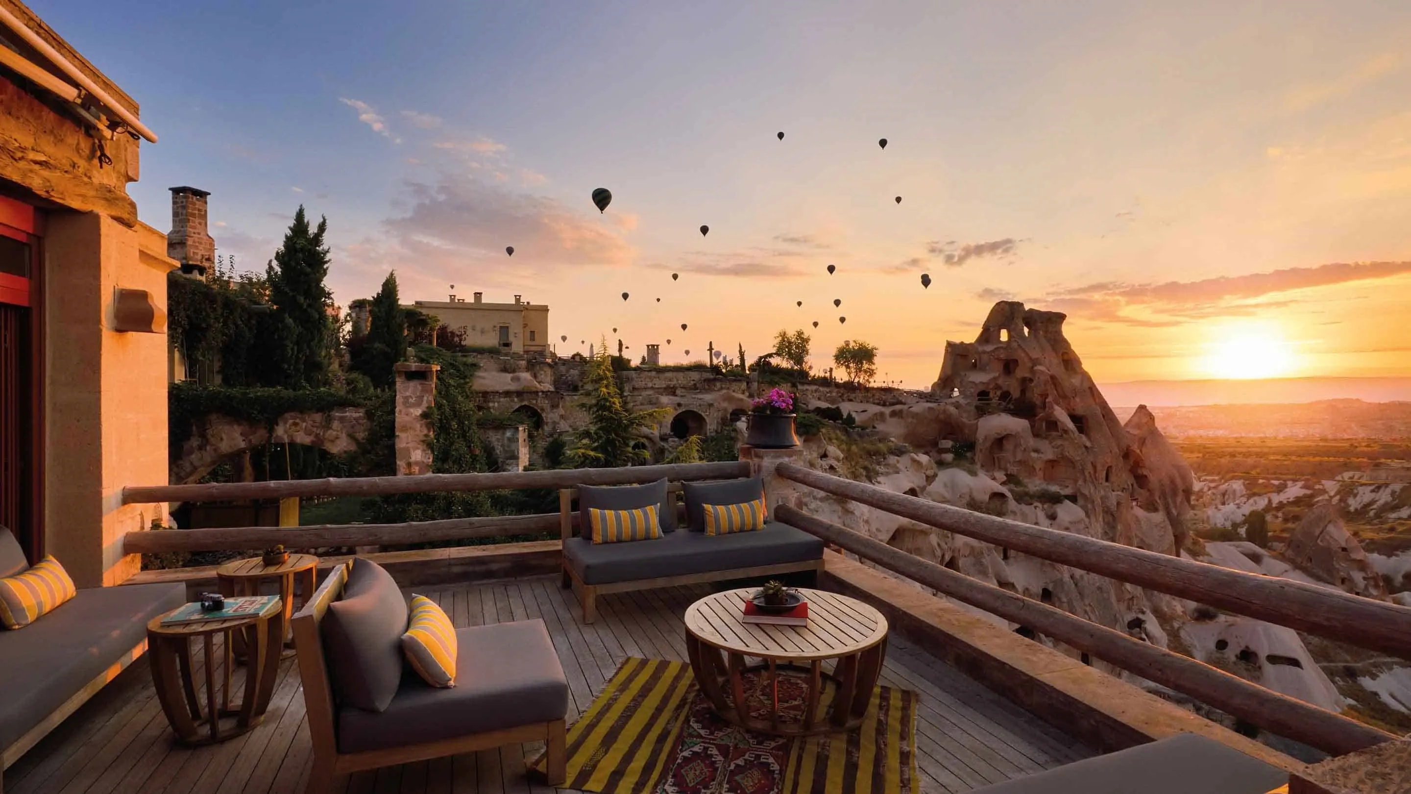 A terrace lounge at Argos in Cappadocia overlooking rock formations and hot air balloons at sunrise