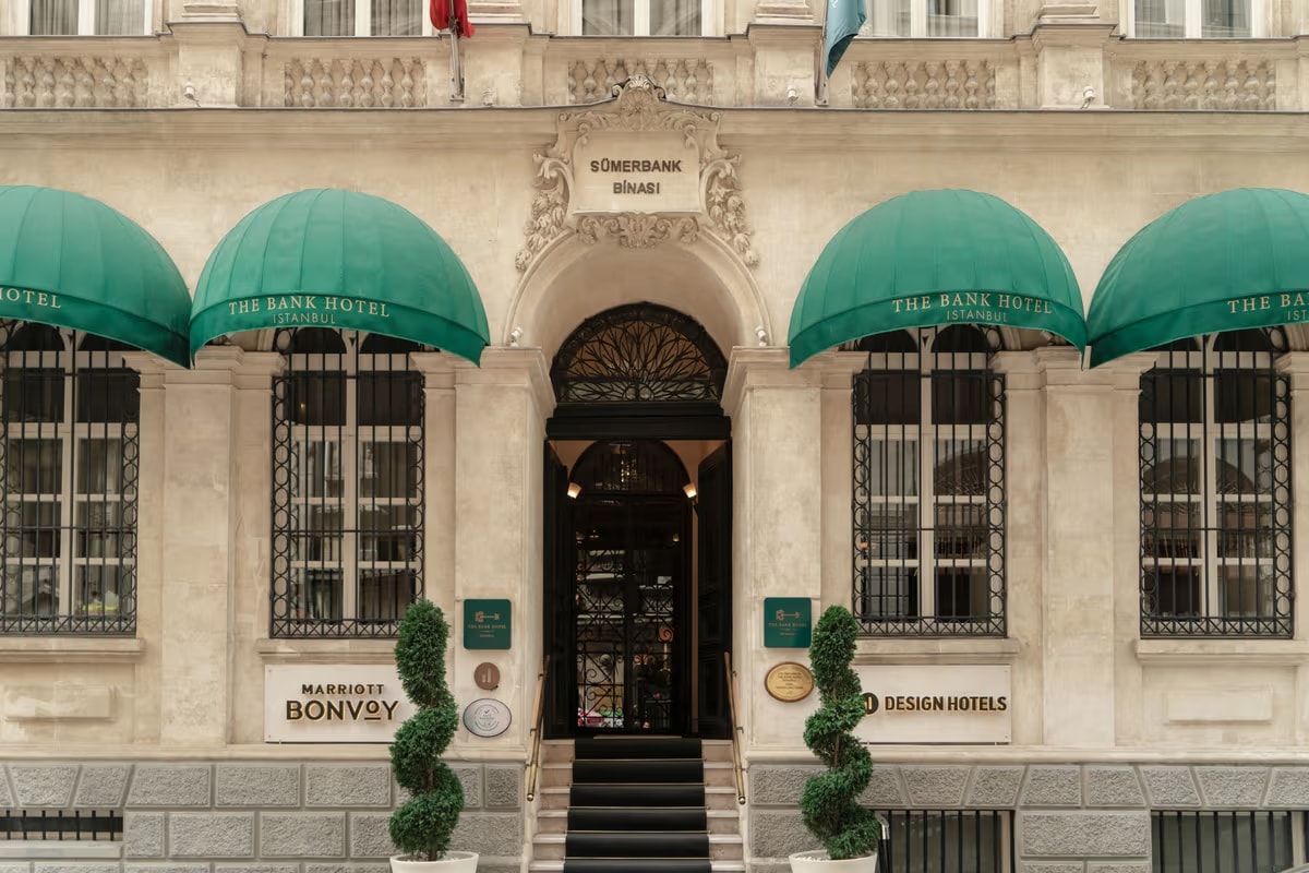 The historic stone façade of The Bank Hotel in Karaköy with green awnings over arched windows