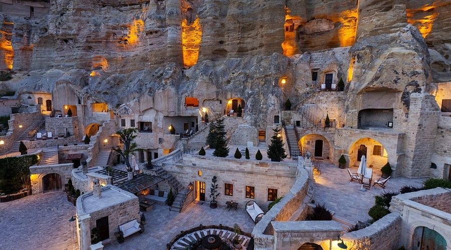 The cave rooms of Yunak Evleri carved into a rock face in Ürgüp, lit at dusk