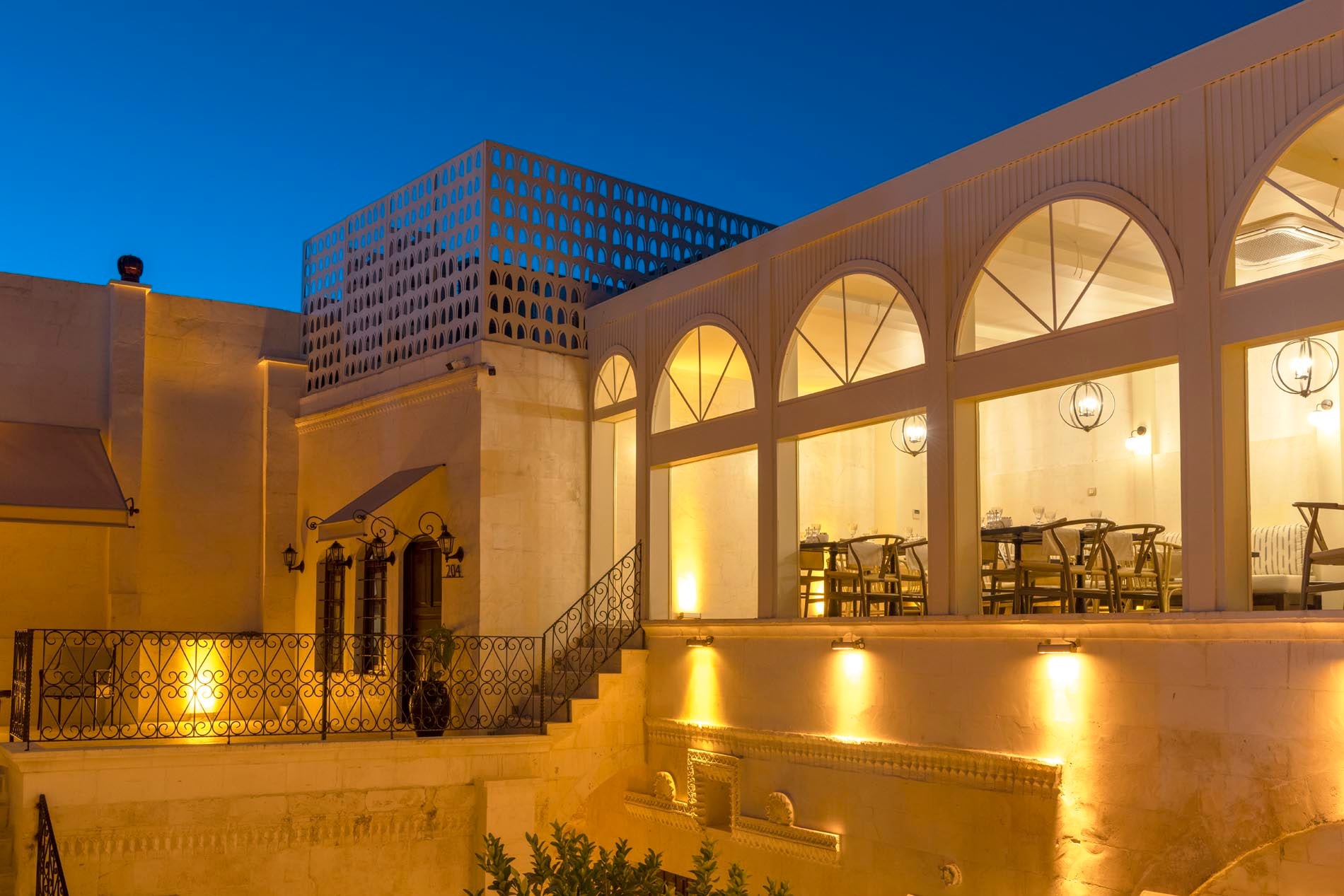 The illuminated stone courtyard and arched windows of Zerzembe Boutique Hotel at blue hour