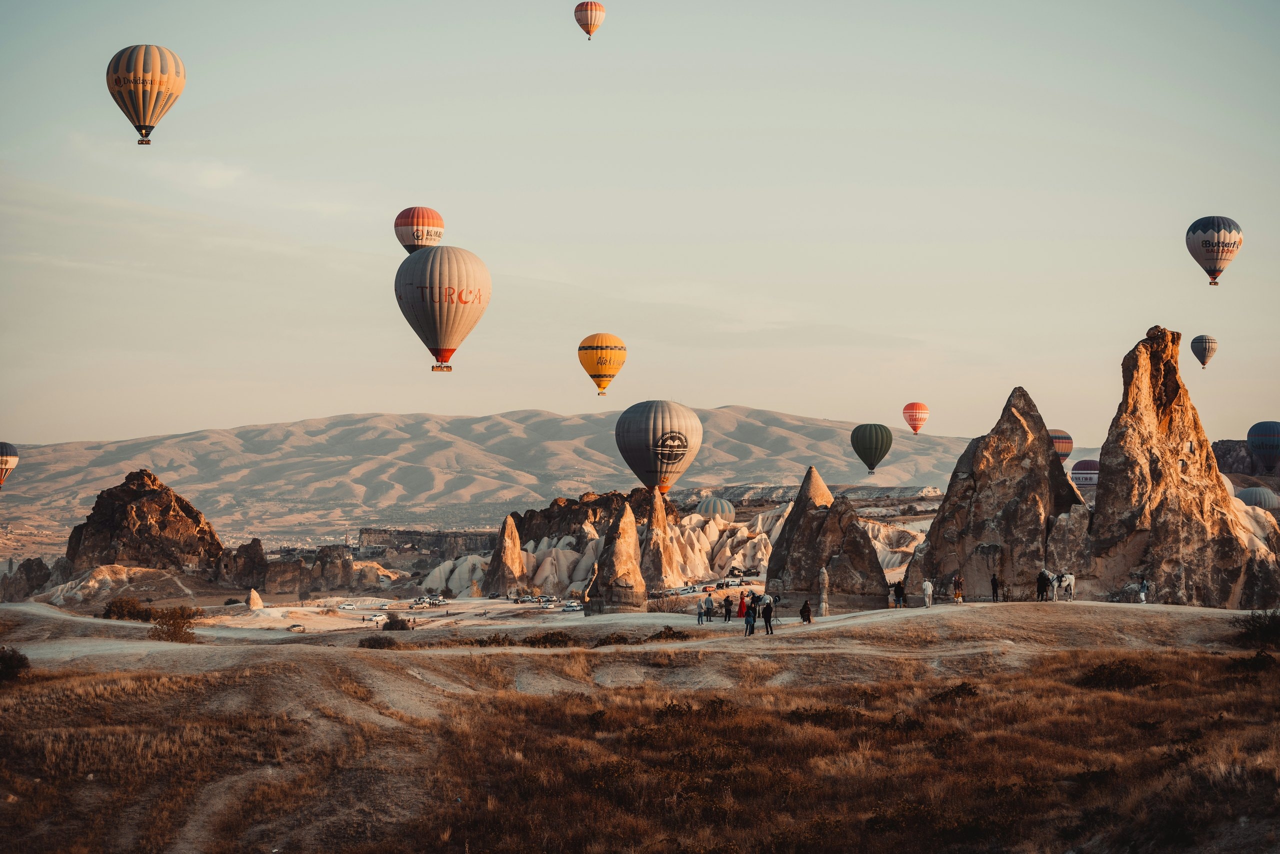 Hot air balloons drifting over the fairy chimneys of Cappadocia in soft morning light