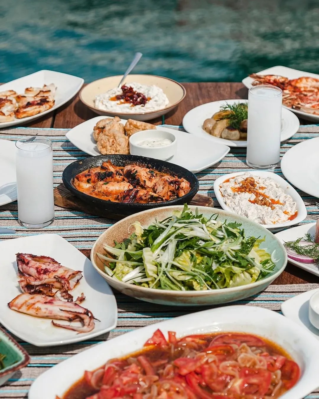 A seaside table spread with mezes, grilled seafood and glasses of rakı at Ferdi Baba
