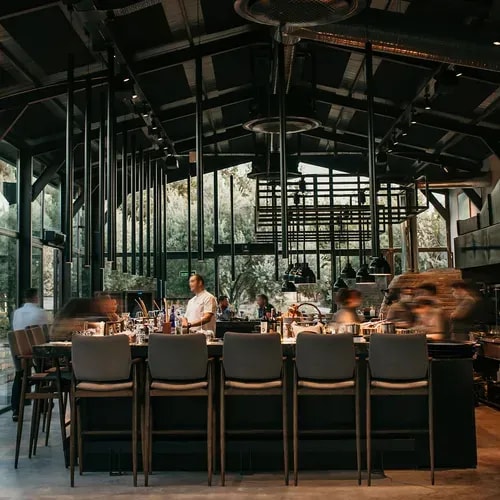 The glass-roofed dining room and long bar counter at OD Urla