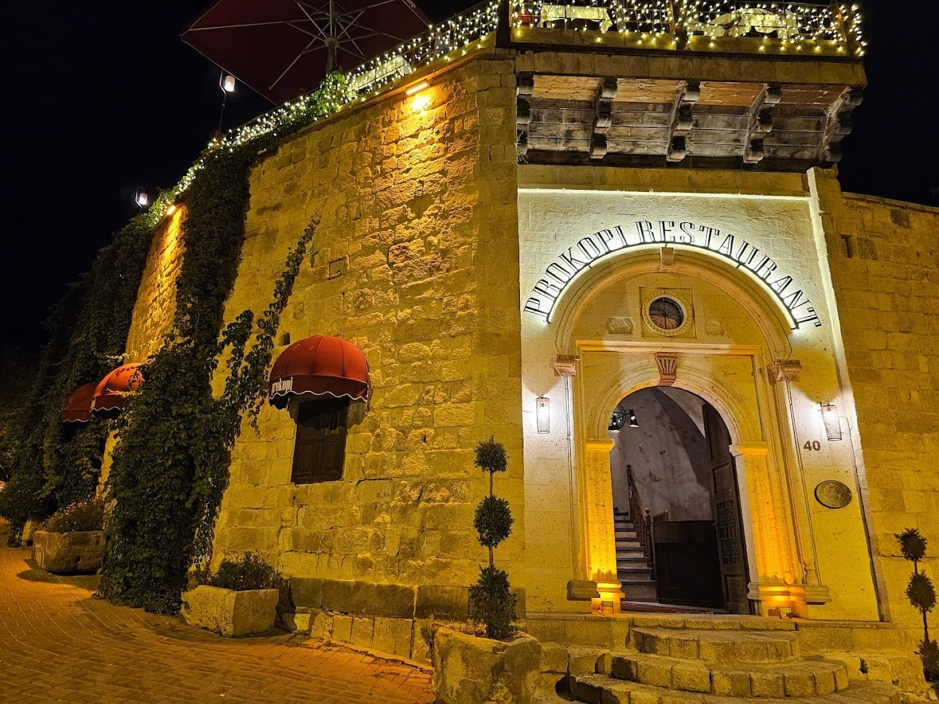 The illuminated stone façade and arched entrance of Prokopi Restaurant in Ürgüp