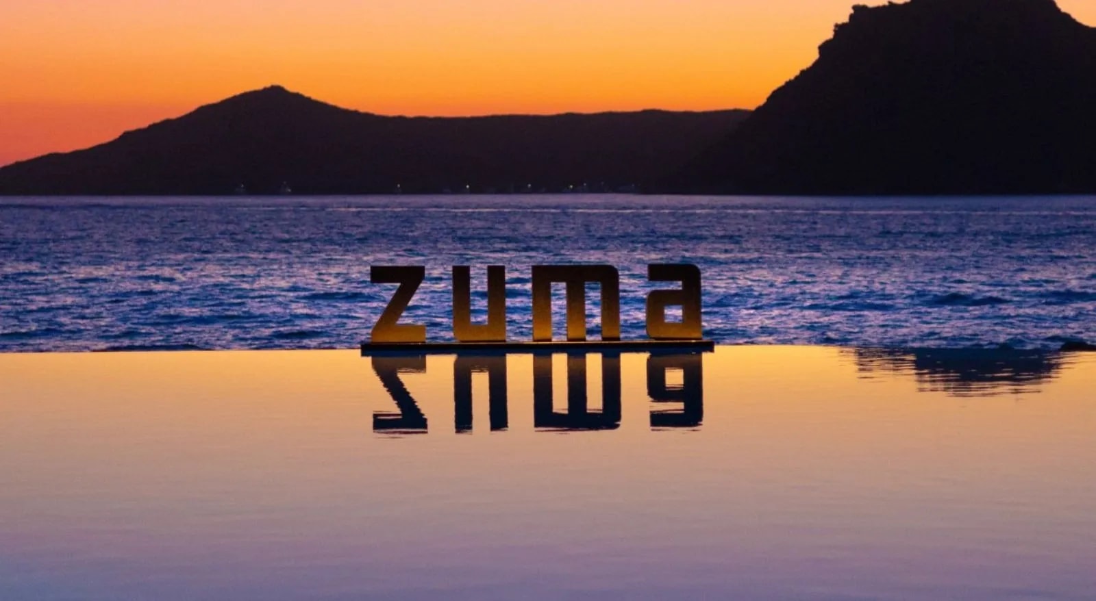 The Zuma sign beside an infinity pool overlooking the sea at sunset in Yalıkavak