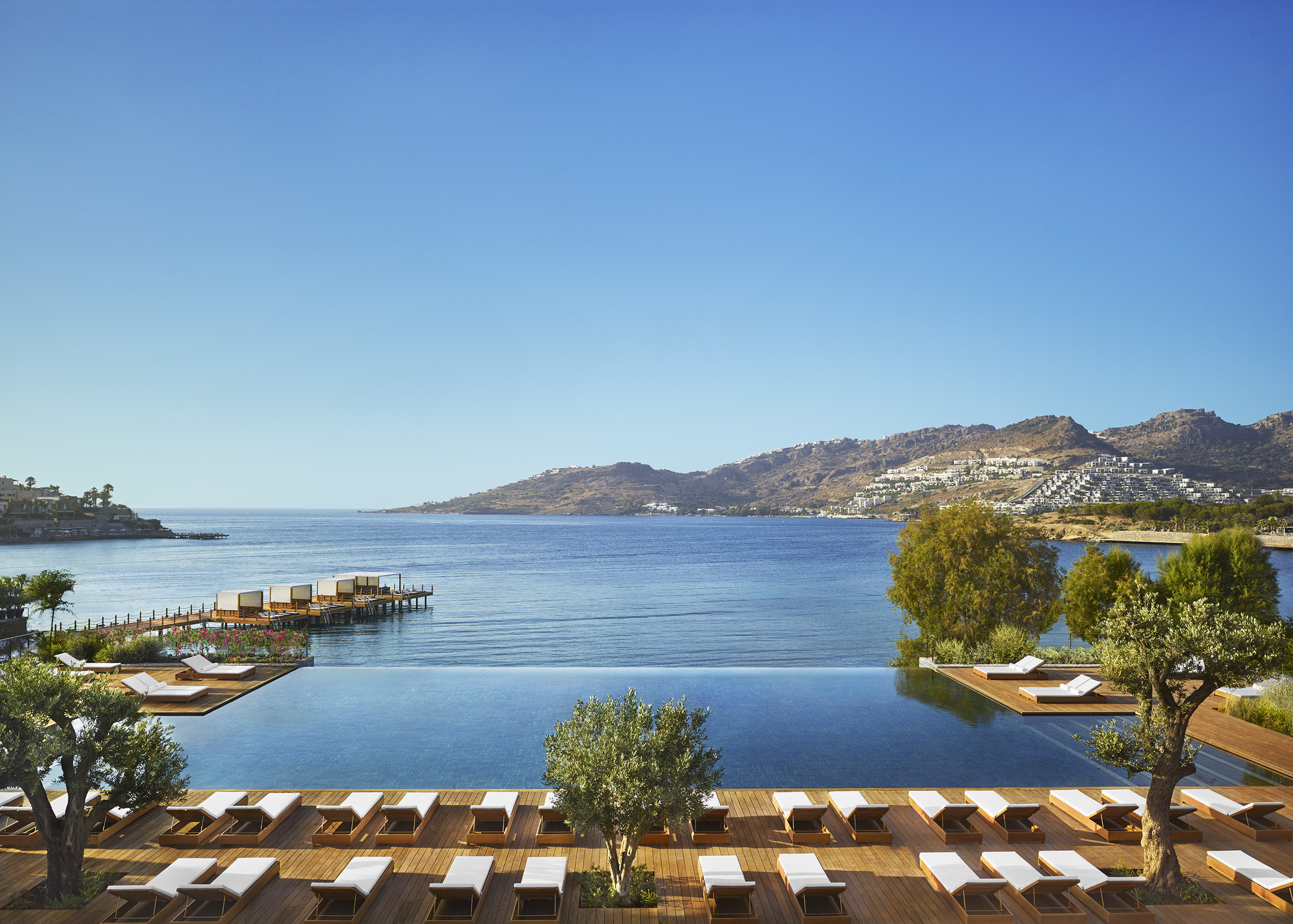 The Bodrum EDITION's infinity pool and loungers above the bay and Bodrum peninsula