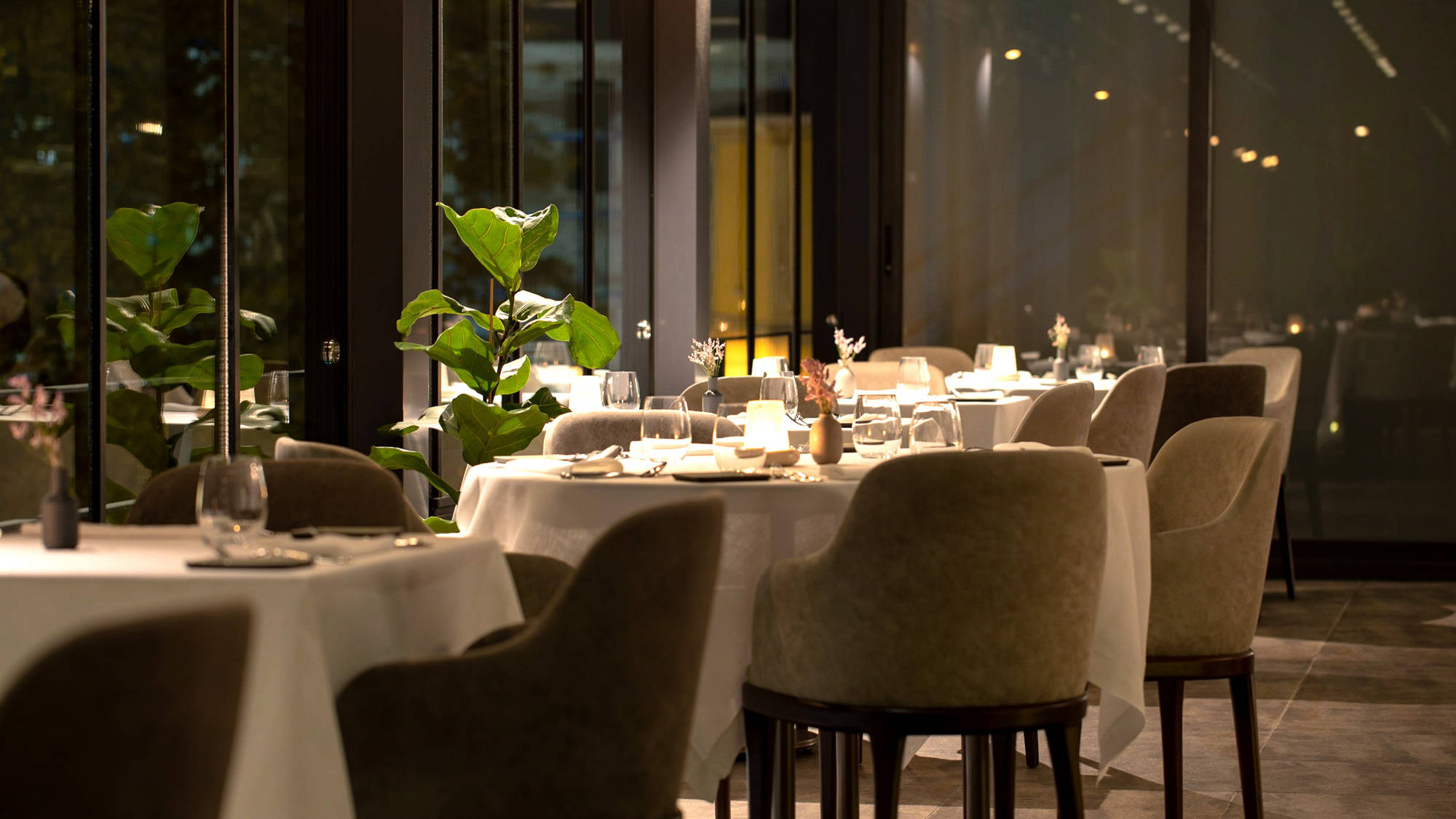 Tables laid with white linen in Nicole's dining room at night