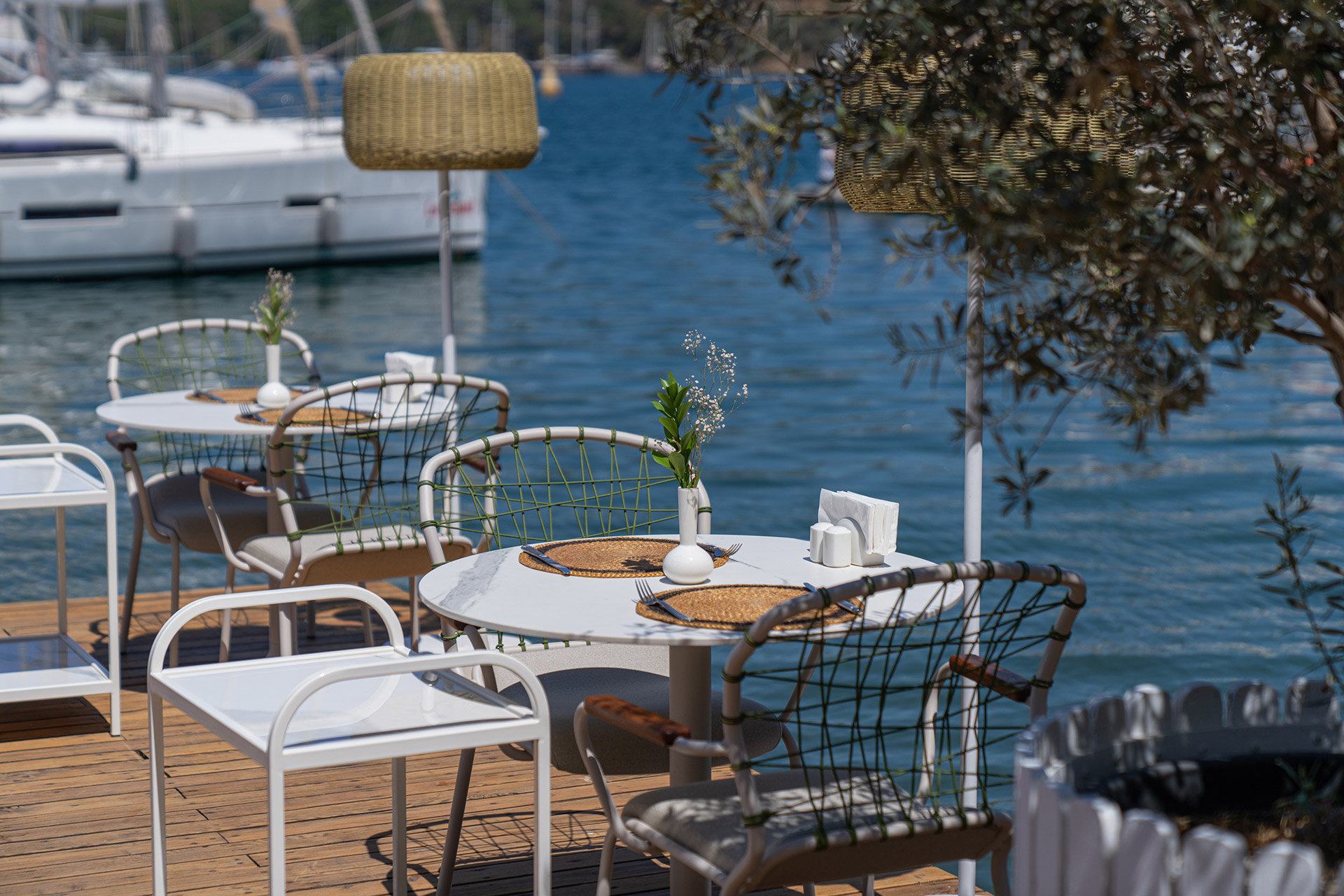 Café tables on a wooden deck beside moored boats at the Yacht Classic Hotel marina